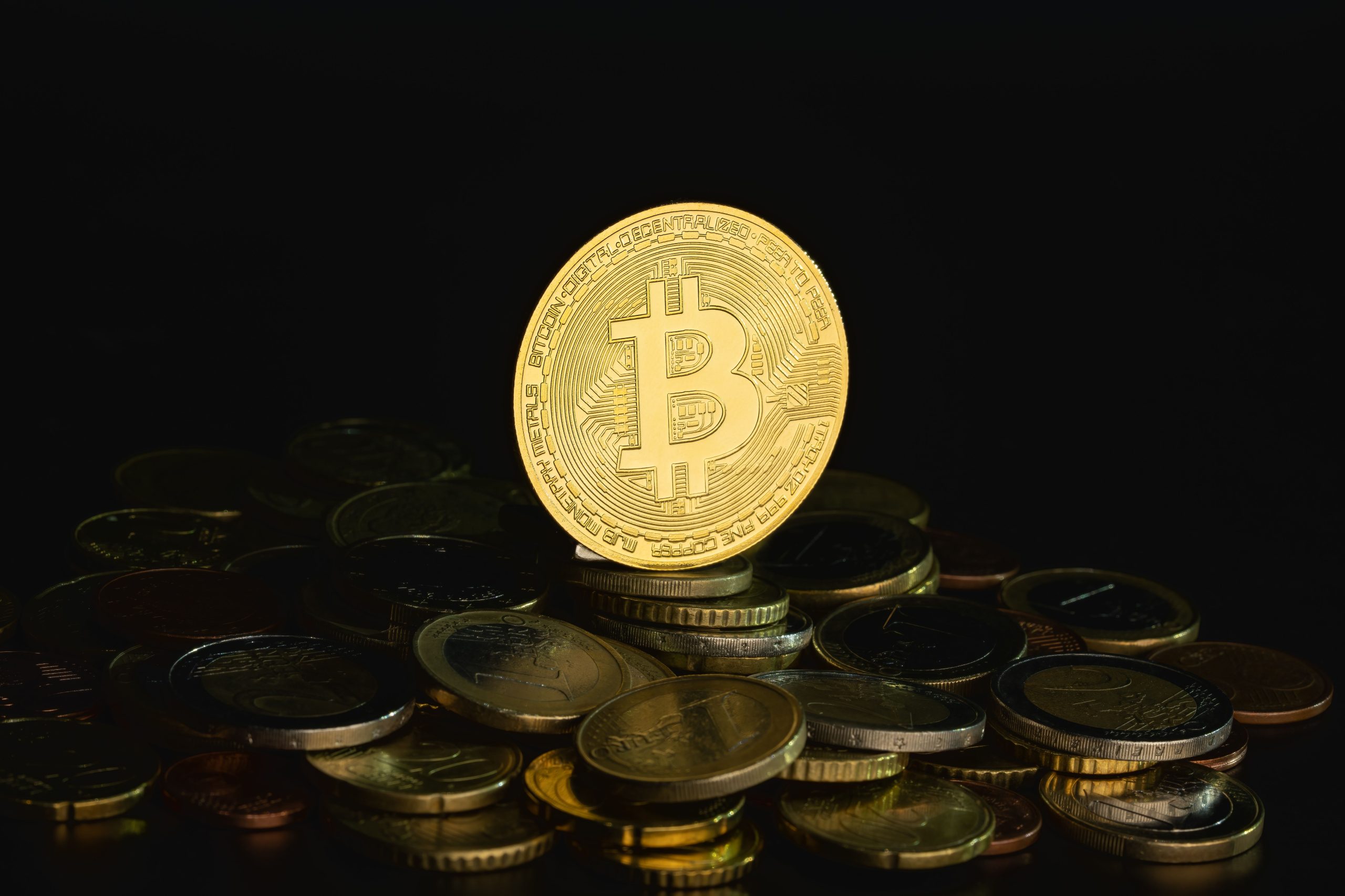 Gold Bitcoin on a stack of coins against a dark background, symbolizing digital wealth and decentralization