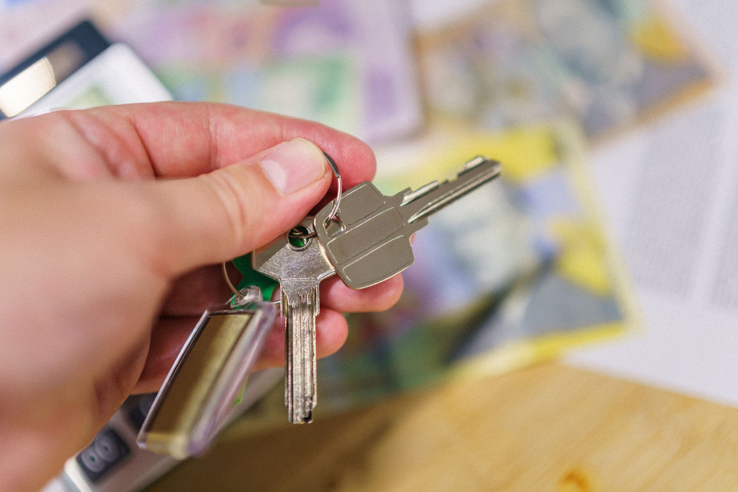Close-up of keys in hand representing property ownership with blurred financial documents in the background