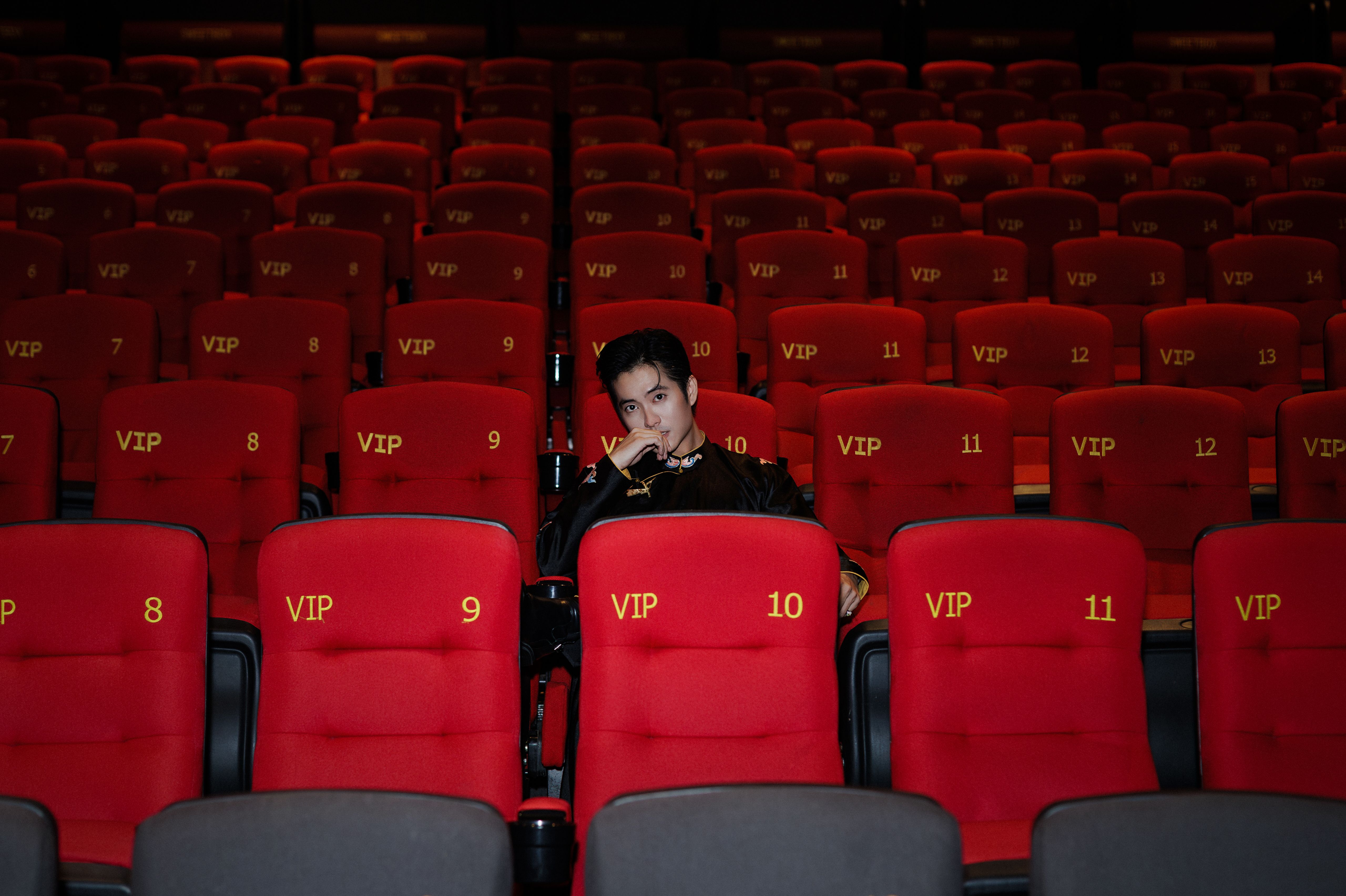 Guest seated alone in an exclusive theater section surrounded by red seats, conveying premium access and privacy.