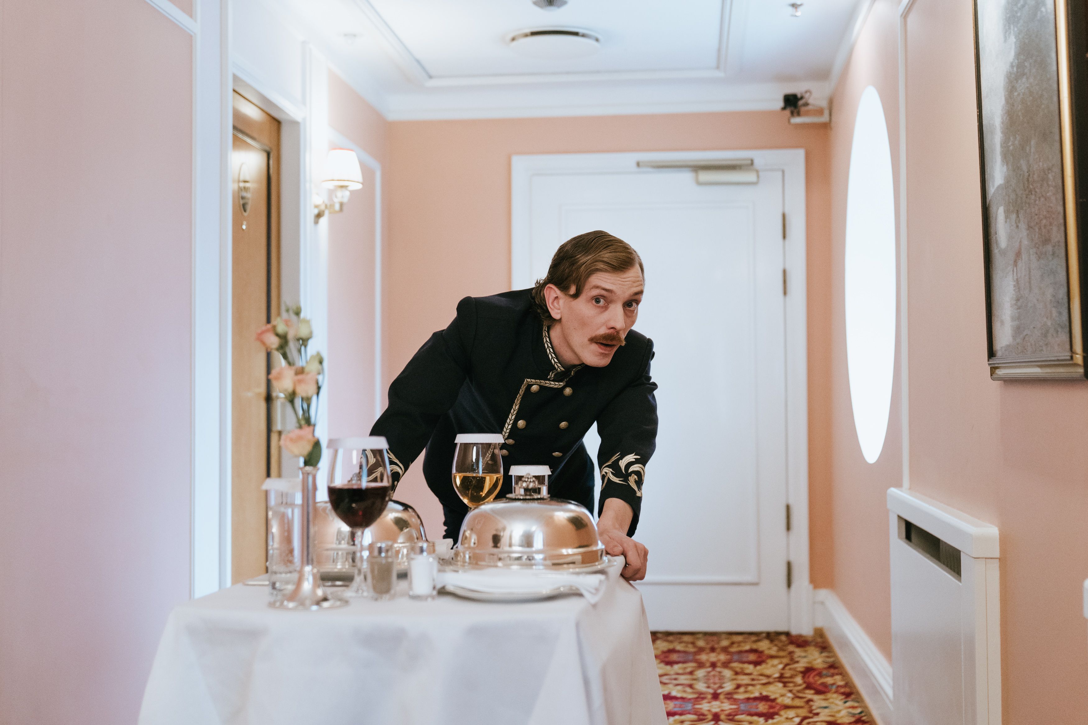 Hotel staff member delivering room service in a luxurious corridor, representing personalized VIP care.